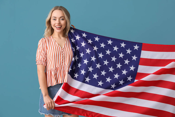 Mavi arka planda ABD bayrağı olan genç bir kadın. - Fotoğraf, Görsel