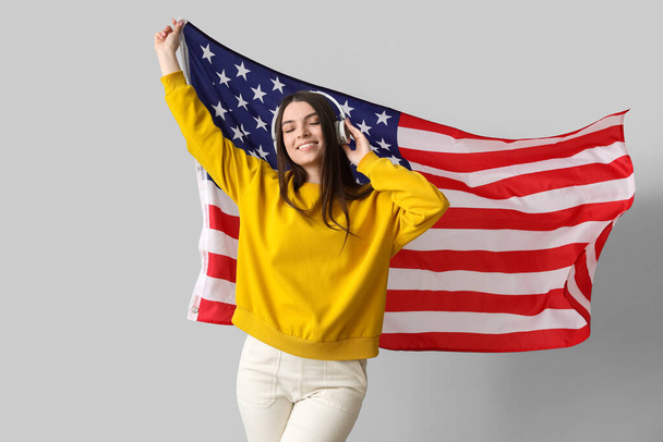 Young woman with USA flag on light background - Foto, afbeelding