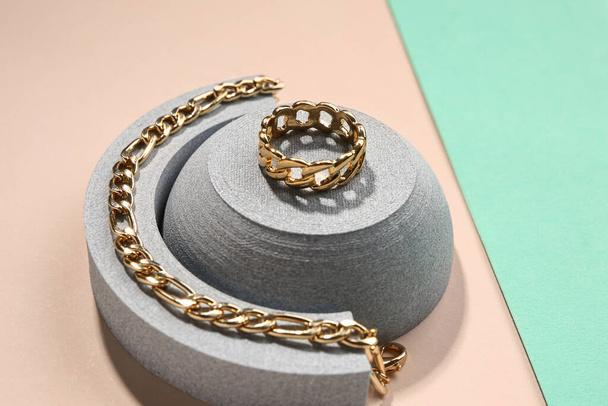 Díszítő dobogók arany gyűrűvel és karkötővel a színes háttér - Fotó, kép