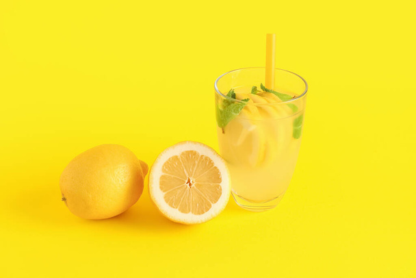 Glas mit frischer Limonade und Zitronen auf gelbem Hintergrund - Foto, Bild
