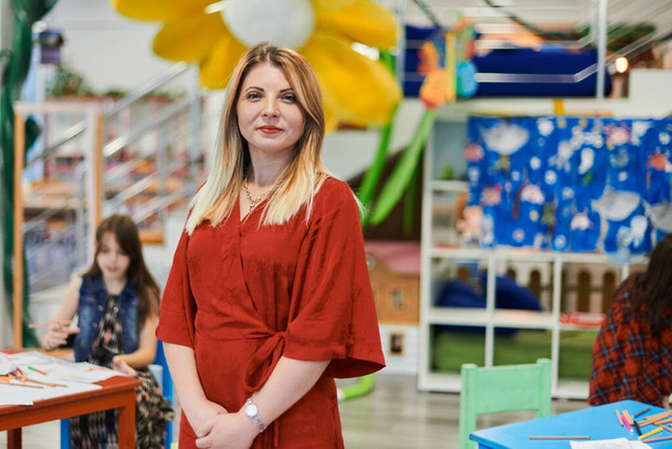 Portrait of a teacher in a preschool institution, in the background of the classrooms. High quality photo - Zdjęcie, obraz