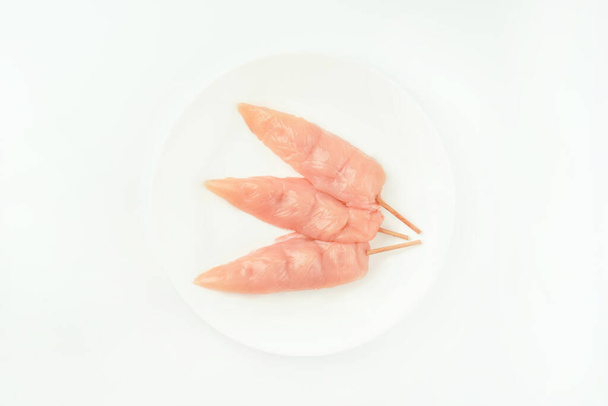 Food concept.Chicken skewers.Skewers from raw chicken meat inner fillet on a white plate for a supermarket on a white background.Ogranic food,healthy eating.Food for retail.Top view. - 写真・画像