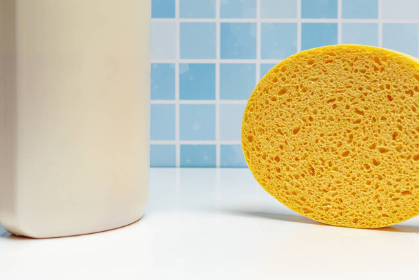 A bottle of bath shampoo along with a synthetic sponge - Foto, afbeelding