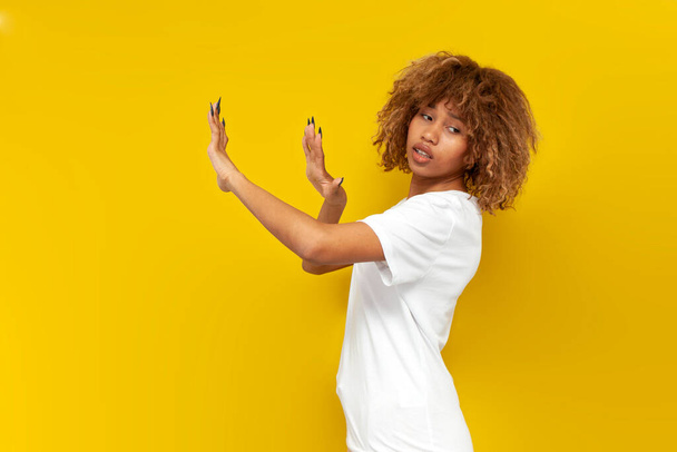 fiatal göndör amerikai lány elutasítani és elkerülni a kezét sárga elszigetelt háttér, afrikai nő frizura mutatja elutasítása és tiltó gesztus - Fotó, kép