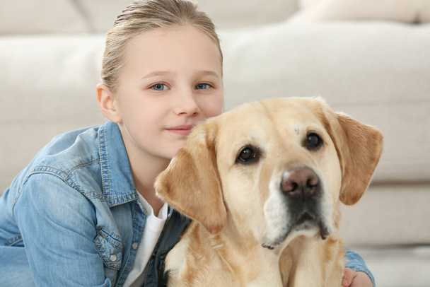 Cute child with her Labrador Retriever indoors. Adorable pet - Photo, Image