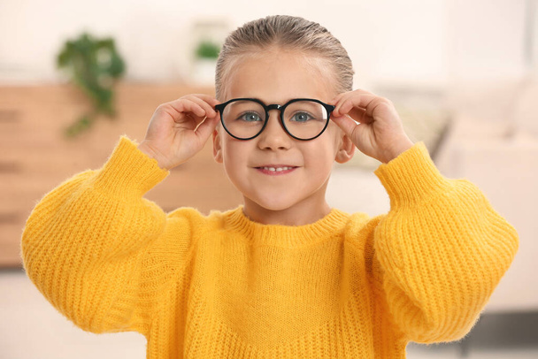 Portrait of cute little girl wearing glasses indoors - Foto, imagen