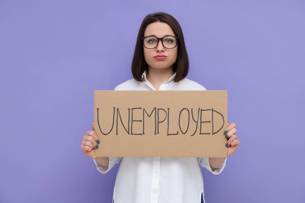 Young woman holding sign with word Unemployed on violet background - Foto, Bild