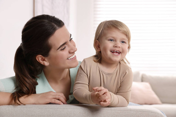 Mother with her cute little daughter on sofa at home - Foto, Imagen