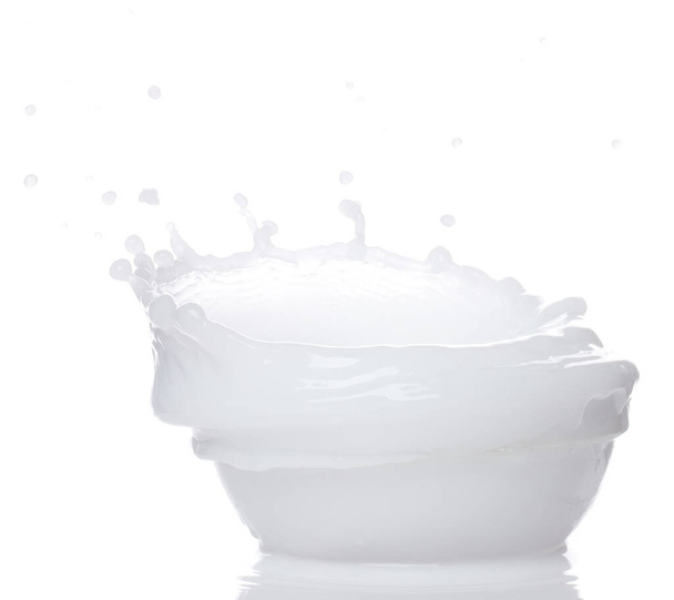 Milk yogurt white water spill splash from bowl up. Milk lotion pour float in mid air. Milk moisturizer explosion throw fluttering. White background isolated high speed shutter freeze motion - Photo, Image