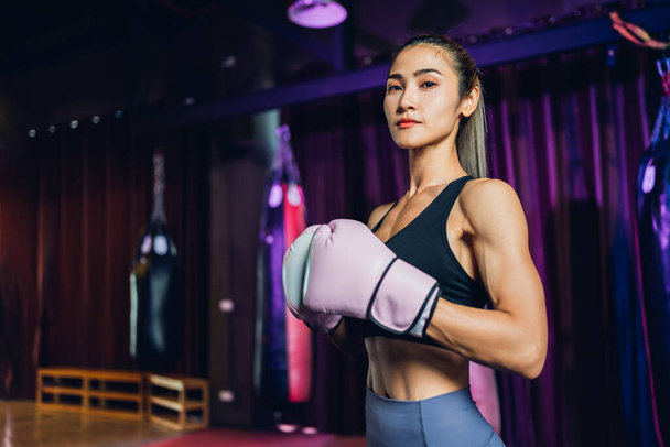 Female Boxer training in Boxing Club. Woman Boxing fighters training at gym. Strong muscular woman practicing box in pink boxing gloves in gym. - Фото, изображение