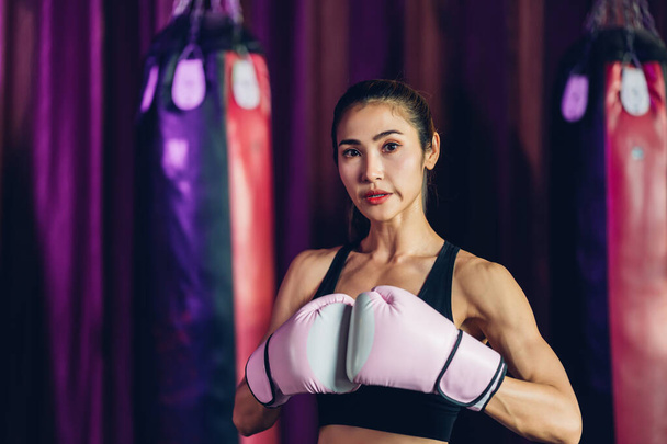 Female Boxer training in Boxing Club. Woman Boxing fighters training at gym. Strong muscular woman practicing box in pink boxing gloves in gym. - Foto, Bild