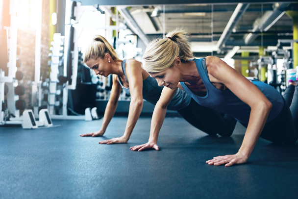 Todays preparation determines tomorrows achievement. two women doing push-ups at the gym - Photo, Image