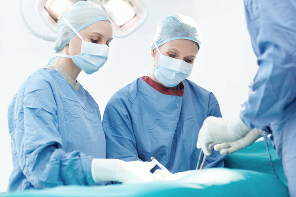 Megtanítani, hogy egy nap vegye át a helyét. Két női sebész együtt dolgozik egy műtét alatt. - Fotó, kép