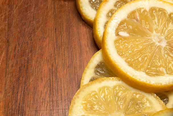 yellow lemon slices on wood cutting board, fresh cut, used to create savory dishes, lemonade, lemon desserts, lemon water - Фото, изображение