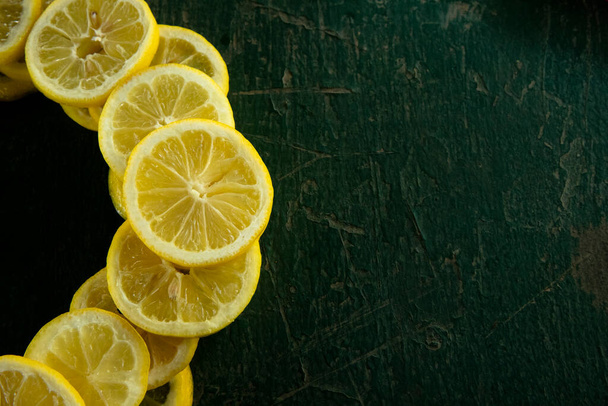 whole and sliced lemons arranged in a circular pattern on a green painted rustic peeling old table - Fotografie, Obrázek
