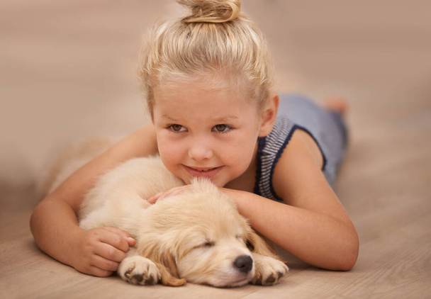 Dziewczyna dziecko przytulić szczeniaka, zrelaksować się w domu i szczęśliwy ze snem golden retriever pies i dziecko z uśmiechem. Szczęście, opieka nad zwierzętami i miłość z młodą kobietą i jej domowym zwierzęciem leżącym na drewnianej podłodze. - Zdjęcie, obraz