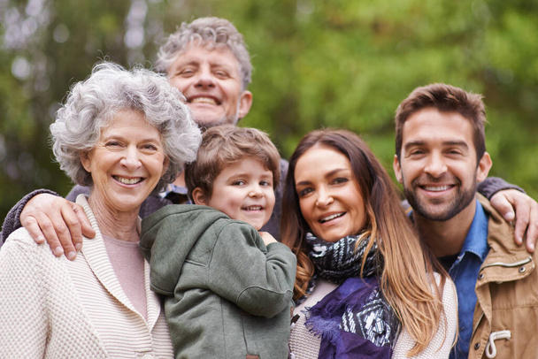 Big family, happy and grandparents or parents with kid in a park on outdoor vacation, holiday with faces together. Mother, happiness and father smile with child for love, care and bonding in nature. - Photo, Image