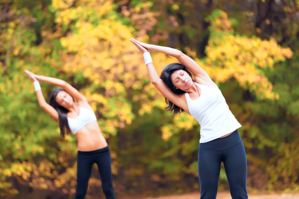 Women, exercise stretching and calm in a outdoor park for yoga and fitness. Health, wellness and arm stretch of female friends in nature on forest feeling relax from body and sport together in woods. - Fotó, kép