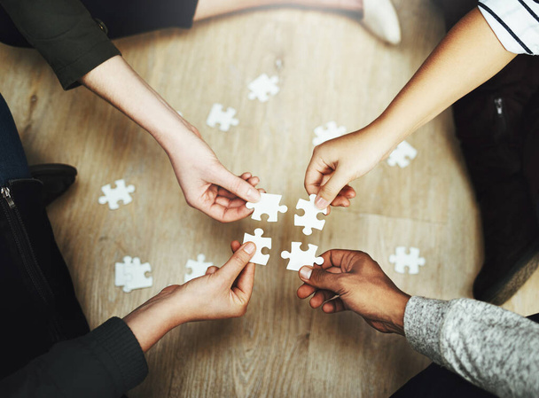 Hands, business people and puzzle in circle, huddle or teamwork for problem solving, solution or game in top view. Group, together and helping with support, synergy and team building on office floor. - Photo, Image