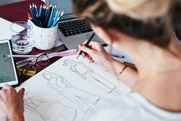 I make whatever I feel everyone need in their closet. a fashion designer working on new sketches at her desk - Foto, imagen