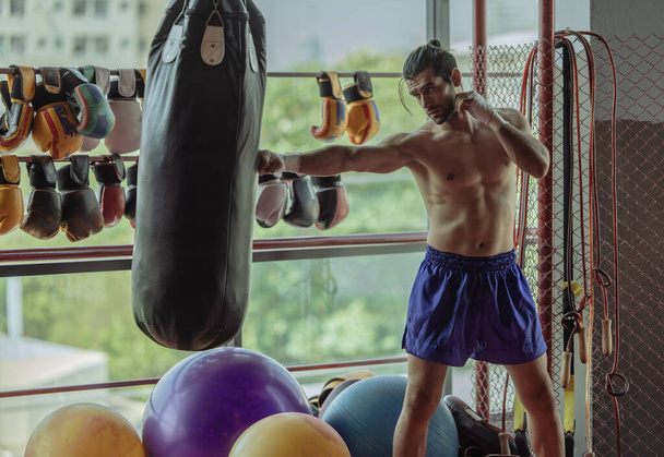 Boxers at the professional level routinely train by punching and kicking sandbags. To be successful in the individual's career, self-discipline, determination, and patience are essential qualities. - Foto, Imagen