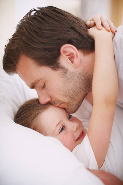 Giving his angel a goodnight kiss. A dad putting his daughter to bed and giving her a goodnight kiss - Zdjęcie, obraz