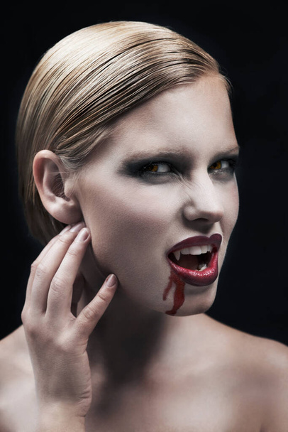 Porträt, Blut und ein weiblicher Vampir im Studio auf dunklem Hintergrund für Halloween oder Cosplay. Fantasie, Horror oder unheimlich mit einer attraktiven jungen Frau Monster posiert als böse und weibliche Kreatur. - Foto, Bild