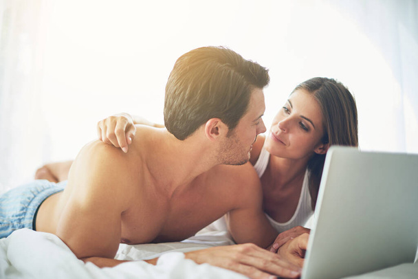 Couple with laptop, streaming film and relax at home with technology, wifi and happy with chill Valentines day date. Love, commitment and relationship with man and woman in bedroom with subscription. - Φωτογραφία, εικόνα