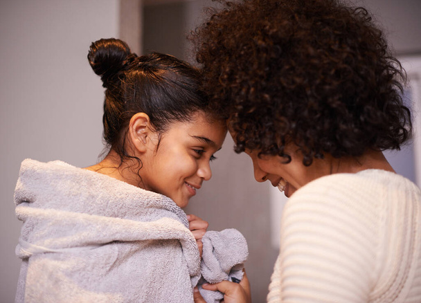 Mother, child in bath towel and close for love, bonding and hugging after cleaning, shower and routine in a bathroom. Washing, embrace and mom with girl, loving and care after a bath in their home. - Photo, Image