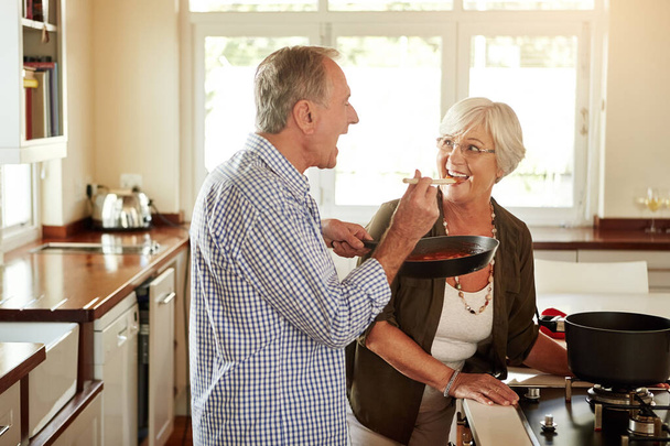 Taste, happy or old couple kitchen cooking with healthy food for lunch or dinner together at home in retirement. Senior woman tasting or smiling with mature husband in meal preparation in Australia. - Фото, изображение