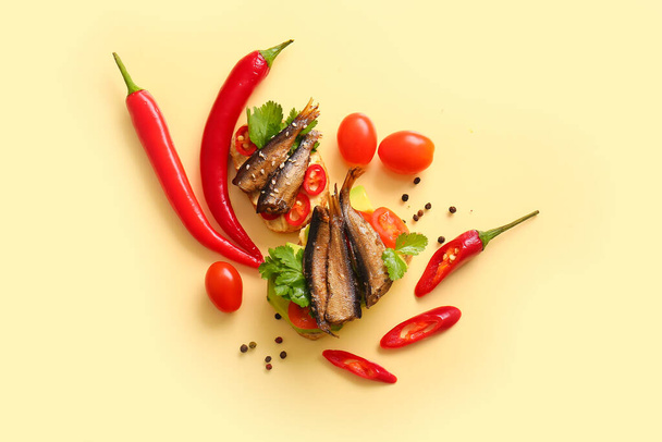 缶スモークスプラットと黄色の背景に新鮮な野菜とおいしいサンドイッチ - 写真・画像