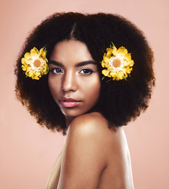 Face of serious woman, flowers and hair in studio background for beauty, eco friendly aesthetic and glow. Portrait of african model, natural skincare and floral plants in afro for sustainable makeup. - Foto, afbeelding