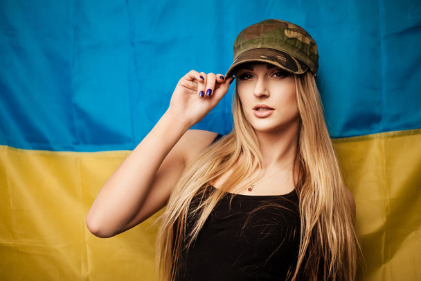 Woman in khaki cap against Ukrainian flag - Фото, зображення