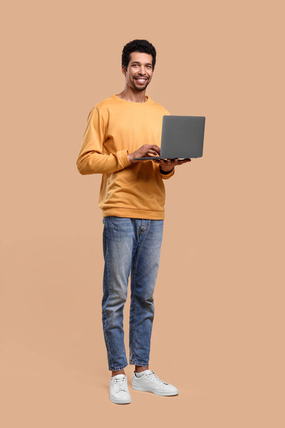 Happy man with laptop on beige background - Фото, зображення