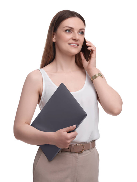 Beautiful businesswoman with laptop talking on smartphone against white background - Zdjęcie, obraz