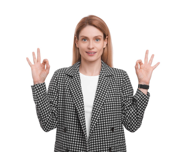 Beautiful happy businesswoman in suit showing ok gesture on white background - Photo, Image