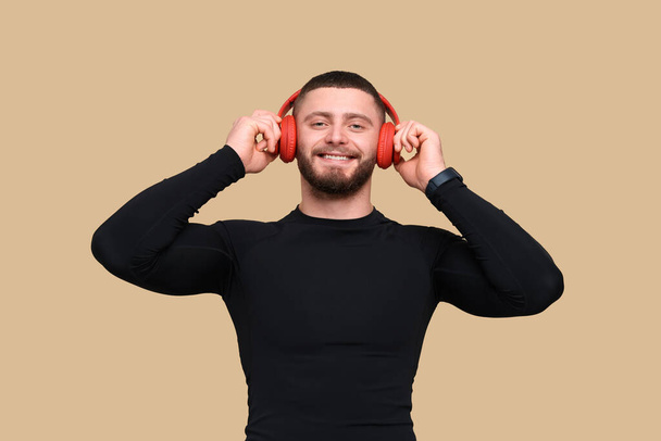 Handsome sportsman with headphones on brown background - Foto, Imagem