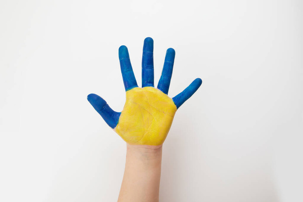 Flaga ukraińska. Symbolem kraju jest niebieski i żółty. Niebiesko-żółty pomalowany dziecięcy ręka, odizolowany na biały. Wsparcie dla Ukrainy. - Zdjęcie, obraz