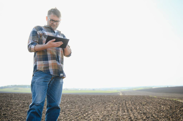 O agricultor trabalha no terreno. Homem agricultor em um campo arado, plantando cereais na primavera no chão. Conceito de negócio agrícola. Cultivo de alimentos, legumes - Foto, Imagem