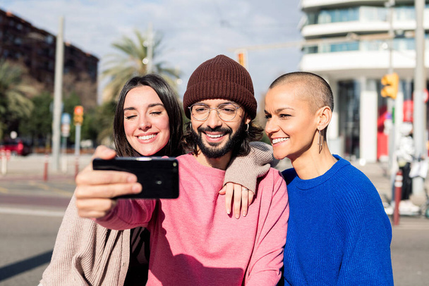 three young friends taking a selfie photo in the city, concept of friendship and urban lifestyle - Fotoğraf, Görsel