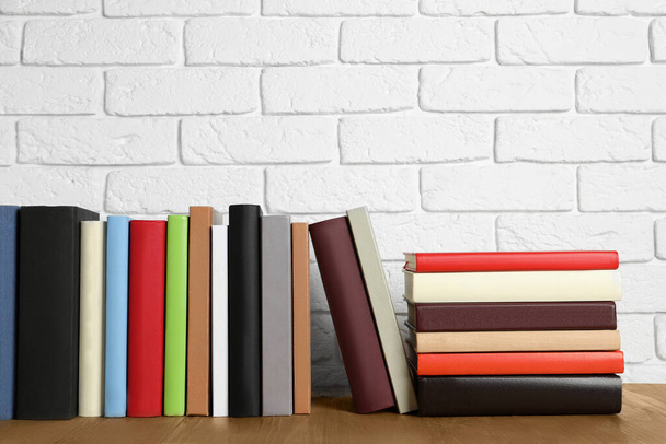 Books on wooden table near white brick wall - Photo, image