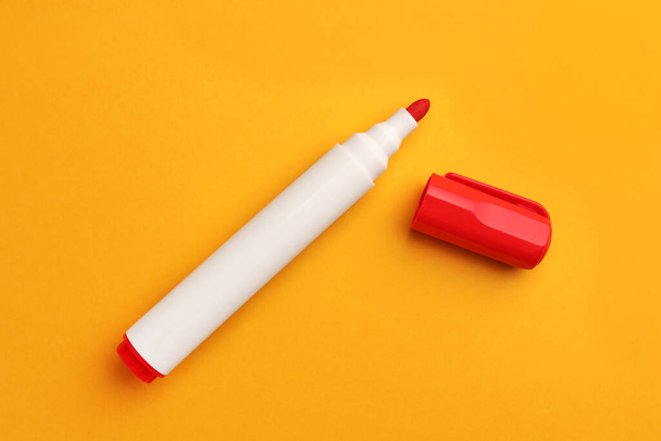 Bright red marker on orange background, flat lay - Foto, afbeelding
