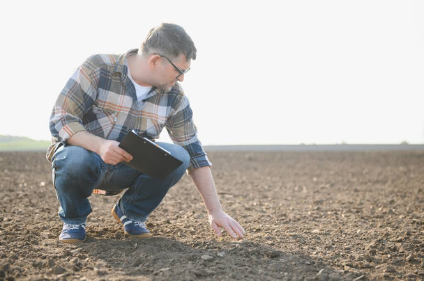 A farmer works in a field sown in spring. An agronomist walks the earth, assessing a plowed field in autumn. Agriculture. Smart farming technologies - Photo, image