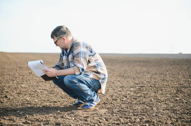 Male Farmer Examines Soil Quality on Fertile Agricultural Farm Land, Agronomist Checking Soil. - Φωτογραφία, εικόνα