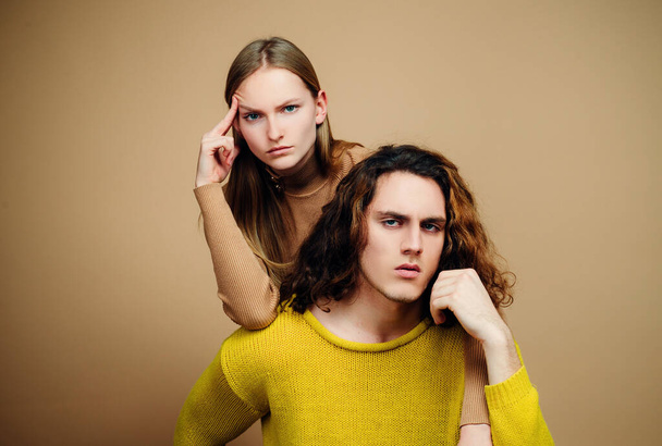 Young couple each other. Portrait of young couple. Fashion couple on beige background in studio. Fashionable coupl - Fotó, kép