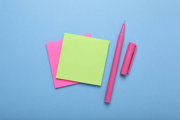 Paper notes and color marker on light blue background, flat lay - Foto, Bild