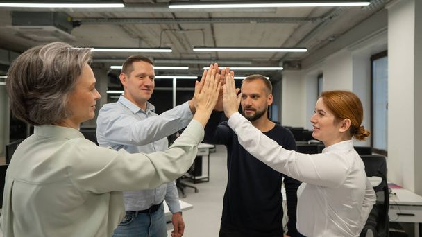 Four co-workers give a high five in the office - Fotografie, Obrázek