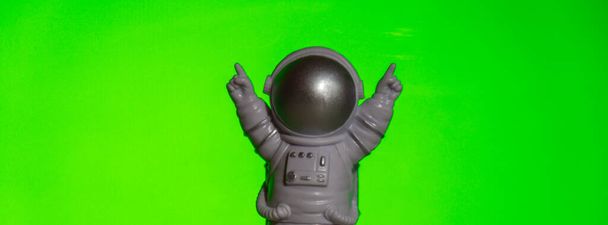 Plastic toy astronaut on green chroma key background Template Mock up Copy space. Concept of out of earth travel, private spaceman commercial flights. Space missions and Sustainability - Photo, Image