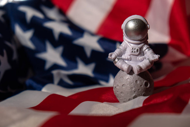 Plastic toy figure astronaut on American flag background Copy space. 50th Anniversary of USA Landing on The Moon Concept of out of earth travel, private spaceman commercial flights. Space missions and - Foto, imagen