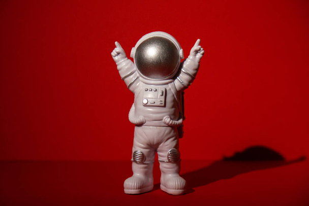Plastic toy astronaut on colorful red background Copy space. Concept of out of earth travel, private spaceman commercial flights. Space missions and Sustainability - Foto, Imagen